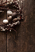 Osterkranz mit Weidenkätzchen und Eiern auf Holzuntergrund