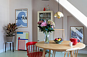 Dining room with round wooden table, golden pendant lamp and modern artwork