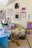 Living room with colourful art gallery and patterned plaid on grey armchair