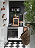 Kitchen with bistro sign, black and white chequered floor and black wall