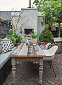 Holztisch, Bank und Stühle auf Terrasse mit Pflanzendekoration