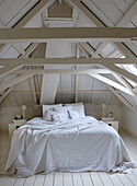 Bedroom in the attic with white wooden beams and double bed