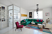 Living room with green corner sofa, colourful cushions and coloured carpet