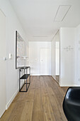 White-painted hallway with wooden floor and minimalist decoration