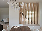 Dining area with wooden table and vertical louvre wall in Dulwich Wood, London