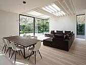 Open-plan living and dining area with wooden table, modern sofa and garden view