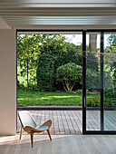 View through open sliding door to wooden terrace and garden, modern architecture