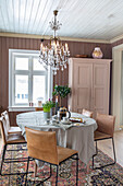 Dining room with chandelier, table and leather chairs on patterned carpet