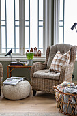 Cosy reading corner with rattan armchair and chequered cushion in front of window front