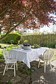 Garden table with tablecloths under a red maple tree