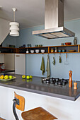 Kitchen with gas hob, open shelves and fruit bowl on the counter