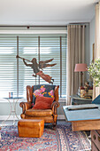 Leather armchair and metal angel figure in front of window