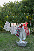 Woman hangs colourful summer dresses on a washing line in the garden