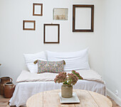 Sofa, wooden frame on white wall, clay pots and rustic table