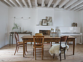 Dining room with wooden table and mixed chairs, white-painted ceiling and piano in the background