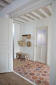 Bright entrance area with terracotta tiles and wooden bench