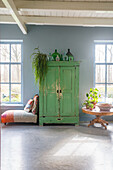 Green vintage cupboard against a blue wall and stone floor