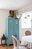 Light blue metal cabinet in rustic dining room with white wooden ceiling