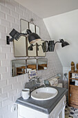 Washbasin with mirror collage and swivelling wall light in the bathroom