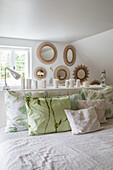 Bedroom with mirror decoration on the wall and cushions in shades of green