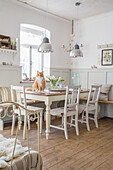 Living/dining area with wooden table, white chairs and hanging lamps, cat on table