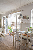 Bright dining room with wooden table, white chairs and vintage decor