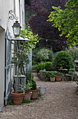 Garden path with plant pots and seating area in front of a house