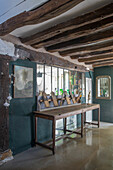 Rustic interior with wooden beams, long wooden table and petrol-coloured walls