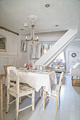 Dining area in shabby chic style with antique wooden chairs and crystal chandelier