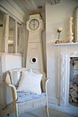 Country-style corner with antique grandfather clock and rattan chair, pale color palette
