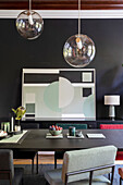 Dining room with black wall, geometric artwork and modern pendant lamps