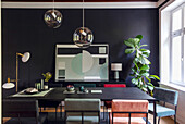 Dining room with modern chairs, dark table and geometric artwork on black wall