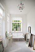 Bright room with white furniture and mirrors leaning against the wall