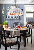 Round dining table, chairs with patterned upholstery and ceiling lamp with lace