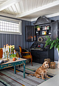 Living room with antique secretary, candlestick and dog on striped carpet