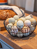 Wire basket with coloured eggs on wooden worktop in the kitchen