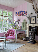 Living room with pink wall, upholstered armchair and antique fireplace