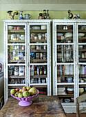 Vintage display cabinets with crockery and decor, fruit bowl on rustic wooden table