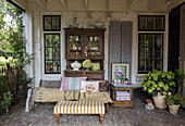 Covered patio with antique wooden cabinet, bench and potted plants