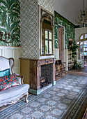 Antique mirror above fireplace, floral wallpaper and carpet in the living room