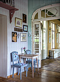 Small dining area with antique wooden table and blue chairs in front of wall with picture gallery, country style