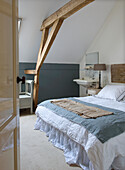 Cozy bedroom with exposed wooden beams and washbasin in the corner