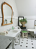 Bathroom with white tiles, free-standing bathtub and antique mirror