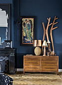 Dark blue living room with angel picture, wooden chest of drawers and rustic decorative elements