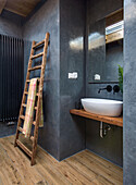 Modern bathroom with wooden ladder towel rail and washbasin on wooden top