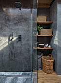 Modern shower with grey concrete wall and woven baskets on wooden shelves