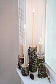 Candles on natural wood stumps as windowsill decoration