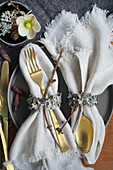 Festliche Tischdekoration mit goldfarbenem Besteck und Serviettenringen aus Naturmaterialien