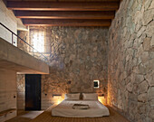 Bedroom with natural stone wall and wooden beams, Casa Cometa, Mexico