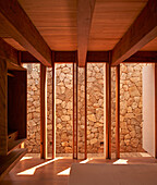 Schlafzimmer mit Holzbalkendecke mit Blick auf Steinmauer